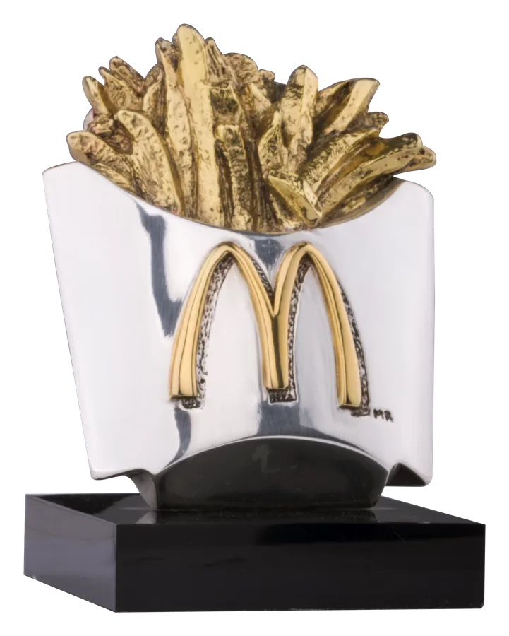 McDonald’s-frietjies in 24-karaat goud wat uit ’n silwer karton met die goue boë opstyg